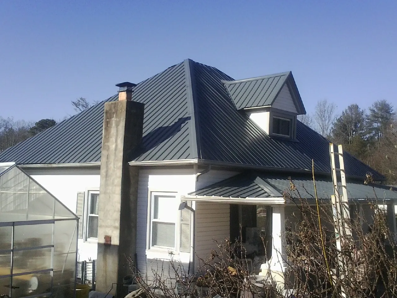 Dark blue standing seam metal roof on a white farmhouse with dormer — Slate & Tile Roof Repair by Roofing Brothers in Cairnbrook