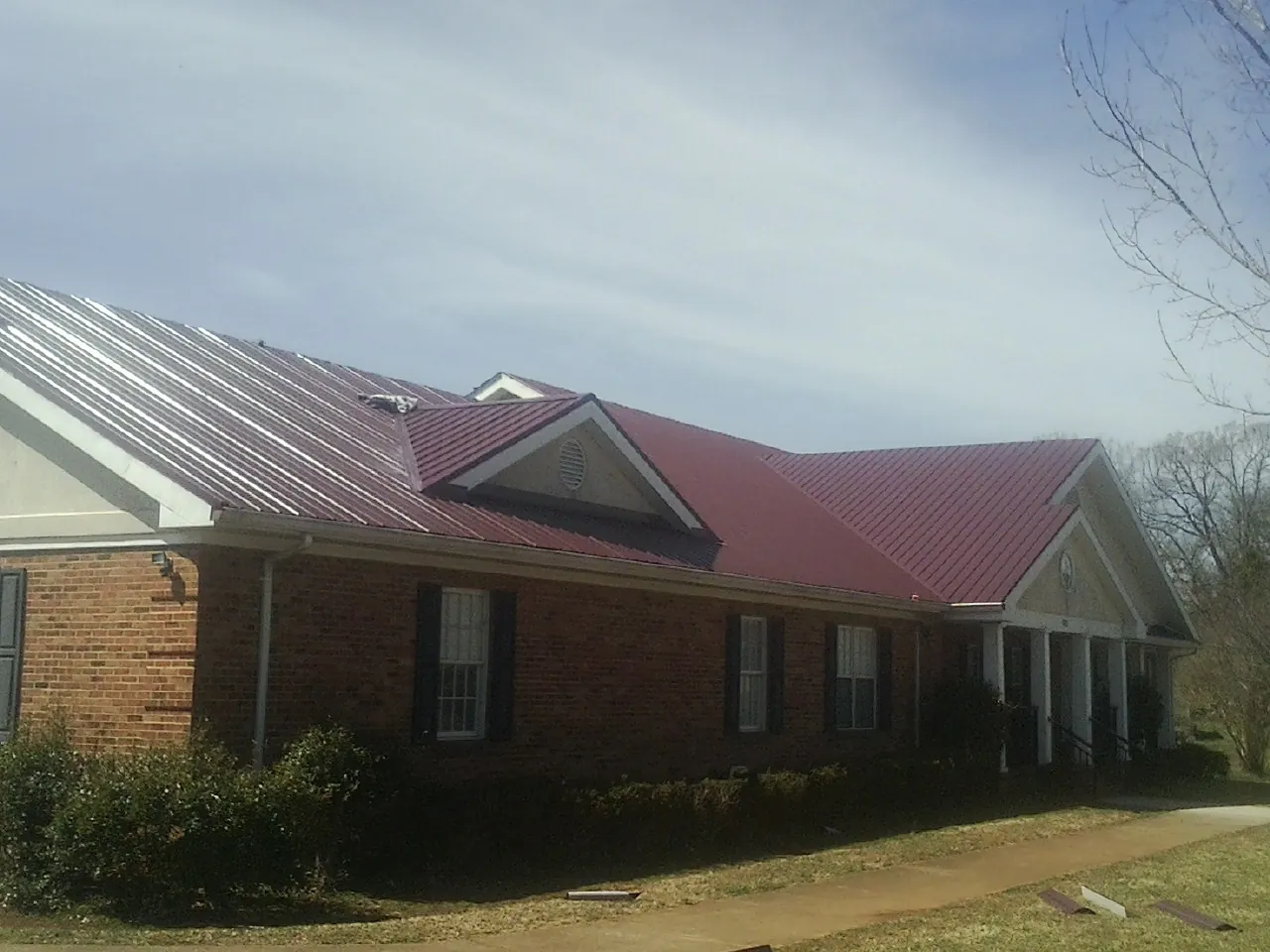 Red metal roof with gabled entries on a long brick building in Cairnbrook