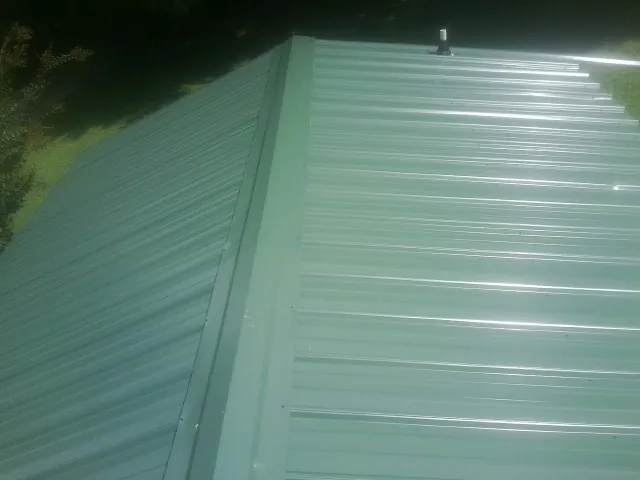 New green metal panels meeting at the ridge of a roof — Flat Roof Repair work by our crew in Cairnbrook