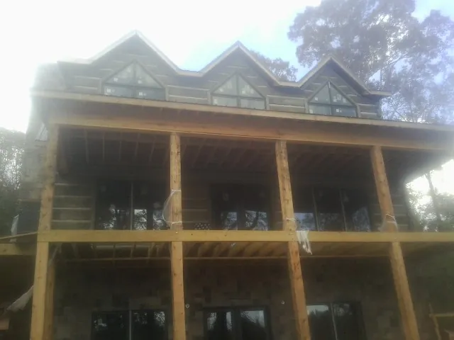Dormers and porch framing on a large log home under construction — Roof Coating work by our crew in Cairnbrook