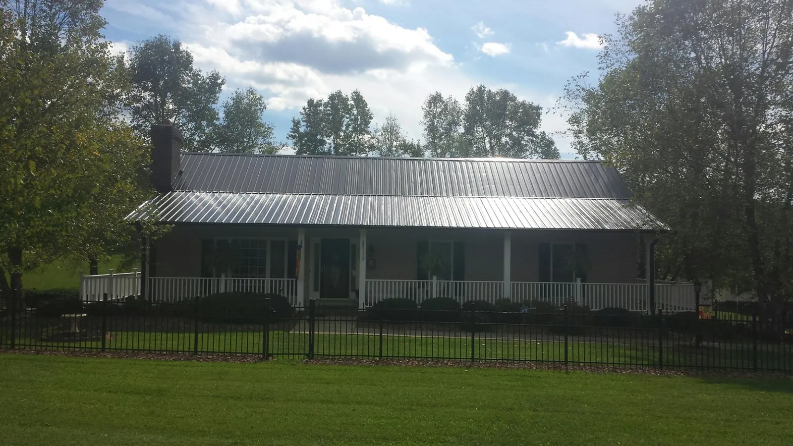 Gray metal roof on a brick ranch with a full width front porch — Gutter Guard Installation work by our crew in Cairnbrook