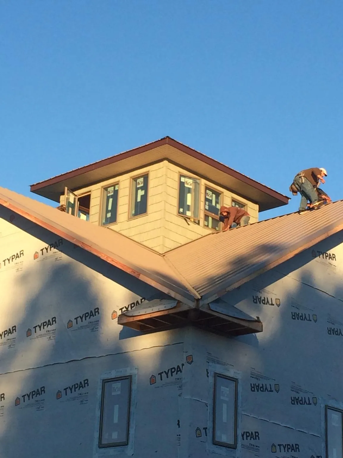 Roofers working around a rooftop cupola on a new metal roof at sunset — Roof Waterproofing in Cairnbrook by Roofing Brothers